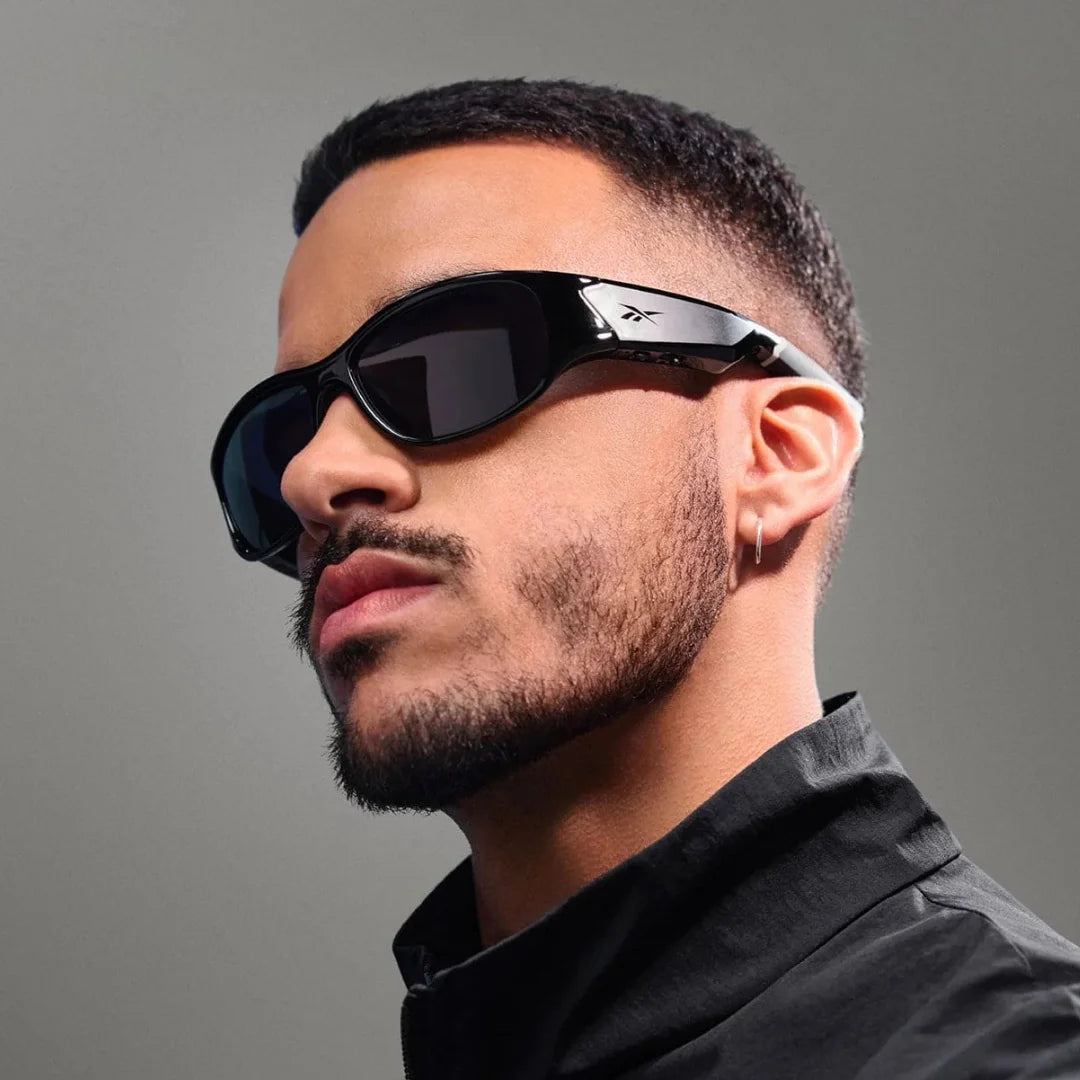 Primer plano de un hombre usando gafas inteligentes Ray-Ban Meta deportivas negras y grabando video con la cámara lateral.