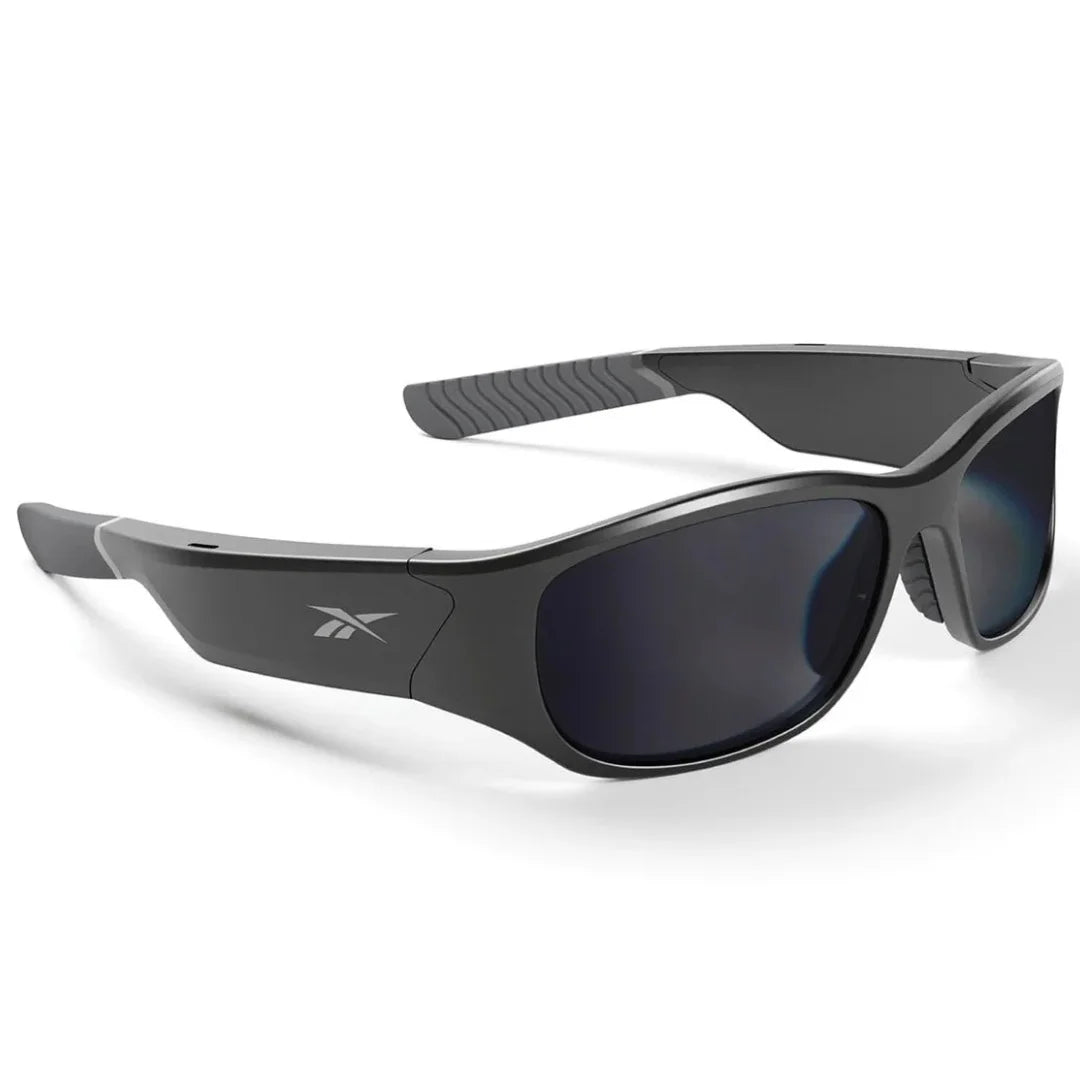 Gafas de sol deportivas Reebok negras, vista en ángulo mostrando el diseño ergonómico y las lentes envolventes oscuras.